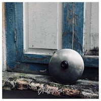 a metal object sits on a ledge in front of a blue door