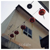 chinese lanterns hanging from a wire in front of a building