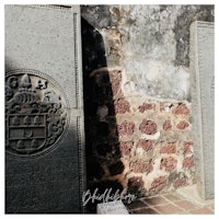 two gravestones in front of a stone wall