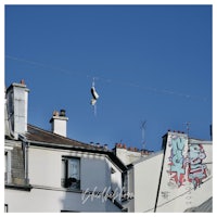 a pair of shoes hanging from a wire on a building in paris