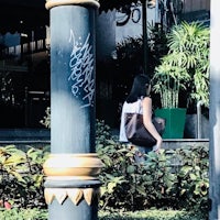 a woman walking down a street with graffiti on a pole