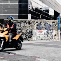 a person riding a motorbike in front of a building with graffiti
