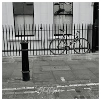 a black and white photo of a bicycle leaning against a fence