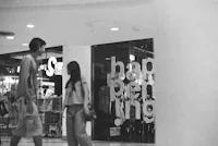 a black and white photo of two people walking in a shopping mall