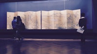 a group of people looking at a display of chinese scrolls