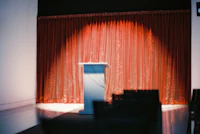 a podium in a room with a red curtain