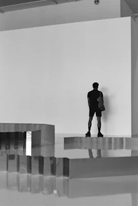 a black and white photo of a man standing in an empty room