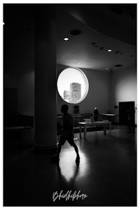 a boy is standing in front of a window in a museum