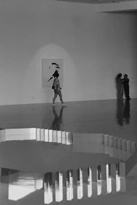 a black and white photo of people walking in an empty room