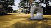 a white sculpture in the middle of a grassy field