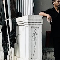 a man in a black shirt leaning against a wall