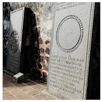a group of gravestones in front of a stone wall