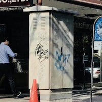 a man walking down the street near a building with graffiti on it
