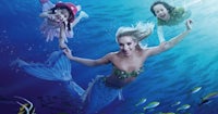 three mermaids swimming in the ocean