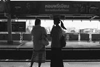 black and white photo of two women waiting at a train station