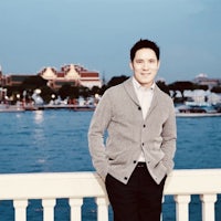 a man standing on a railing near the water