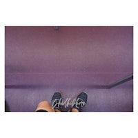 a person's feet standing on a purple floor