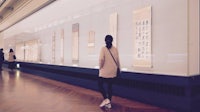 a woman looking at chinese calligraphy in a museum